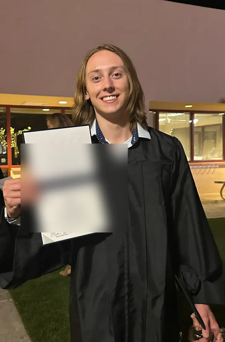 Sebastian in a graduation gown holding a diploma